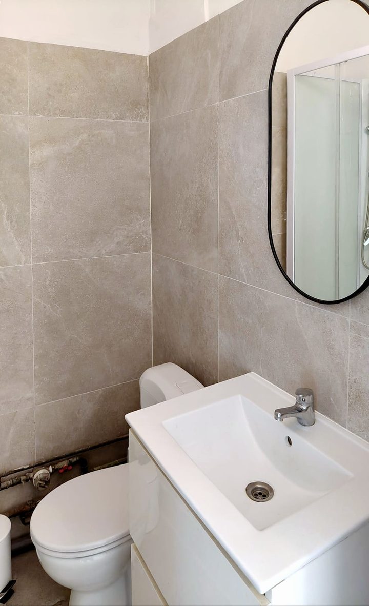 Renovated bathroom with round mirror, vanity unit and toilet
