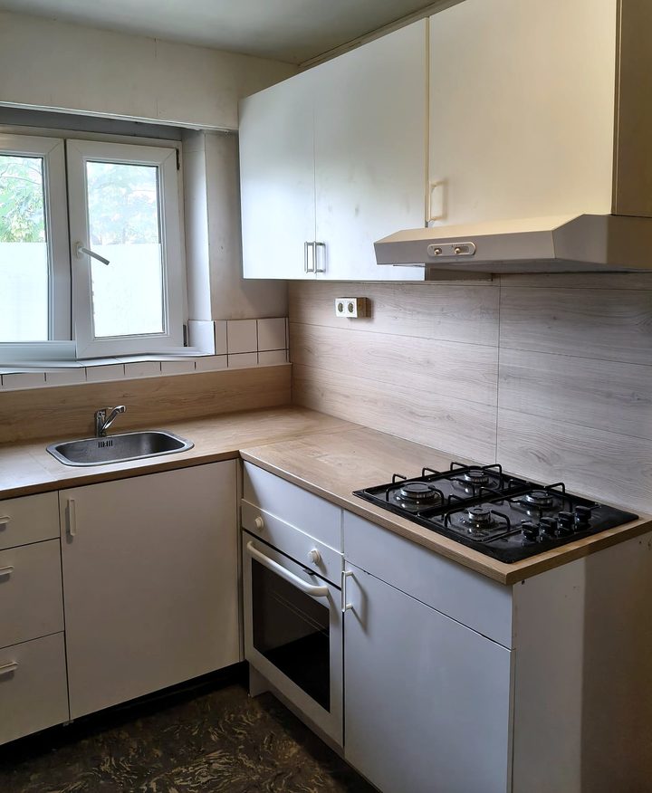 Renovated kitchen with light grey units, dark worktop and tiled splashback