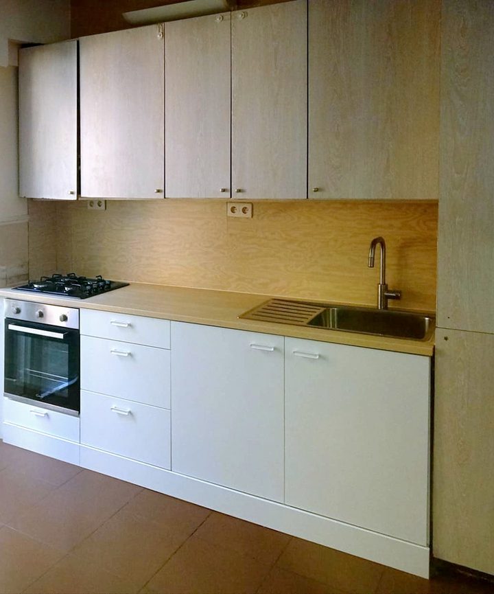 Renovated white handleless kitchen with built-in oven