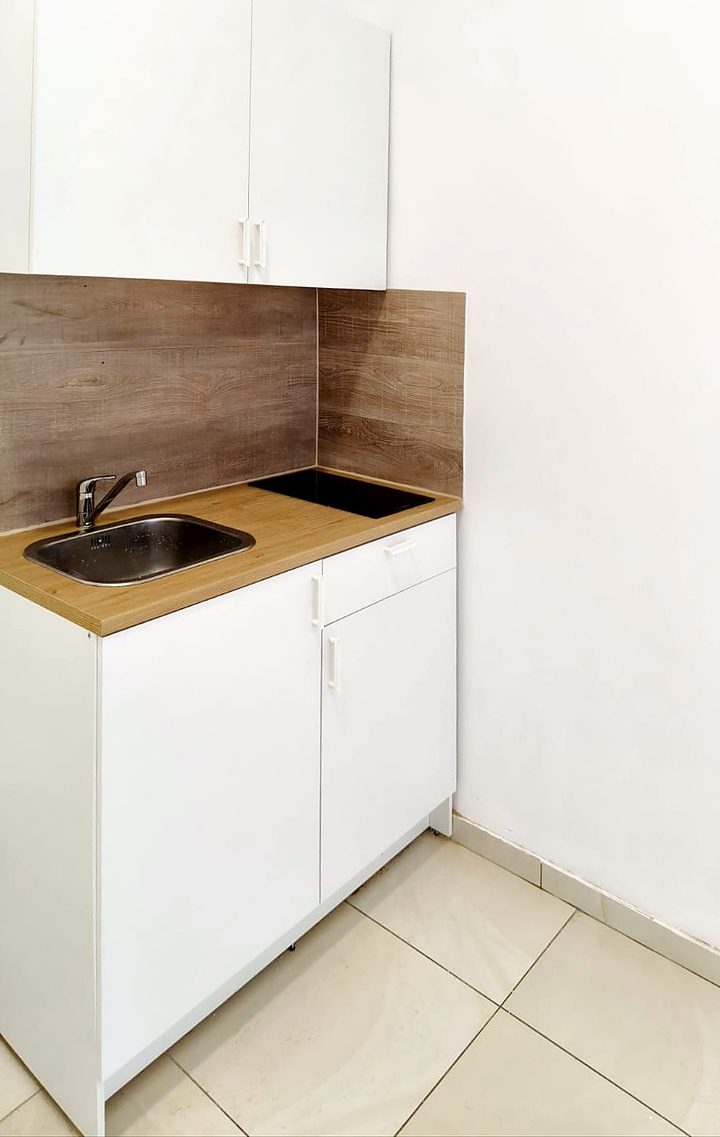 Renovated compact white kitchenette with wooden splashback